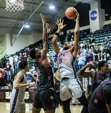 NPC's men's basketball player going up for a shot against defenders.