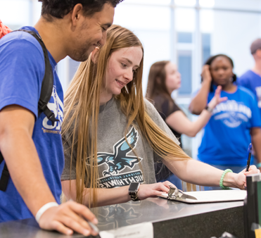 Two people standing at a counter filling out paperwork.