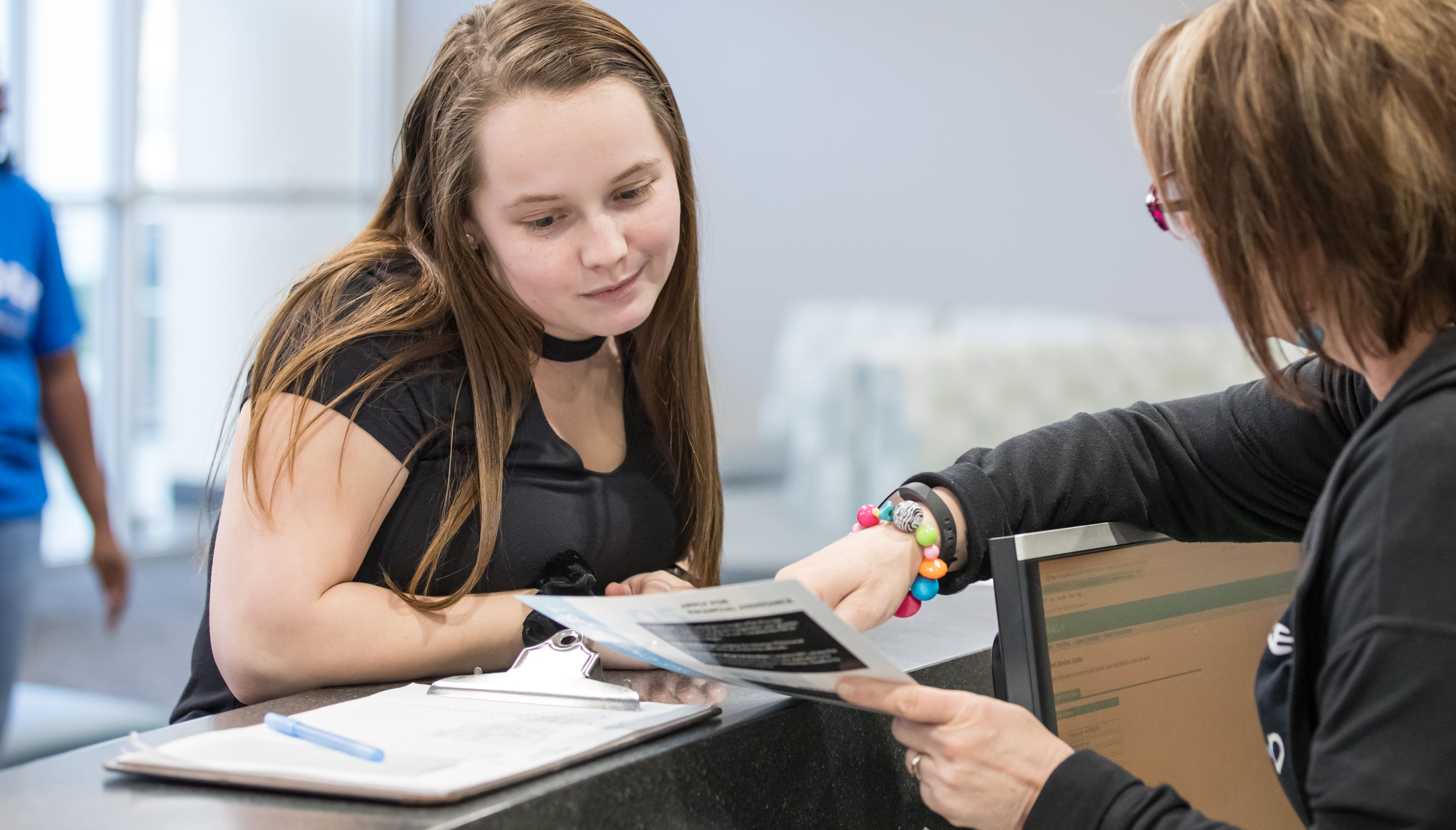 Student being shown a brochure from an employee at the front desk