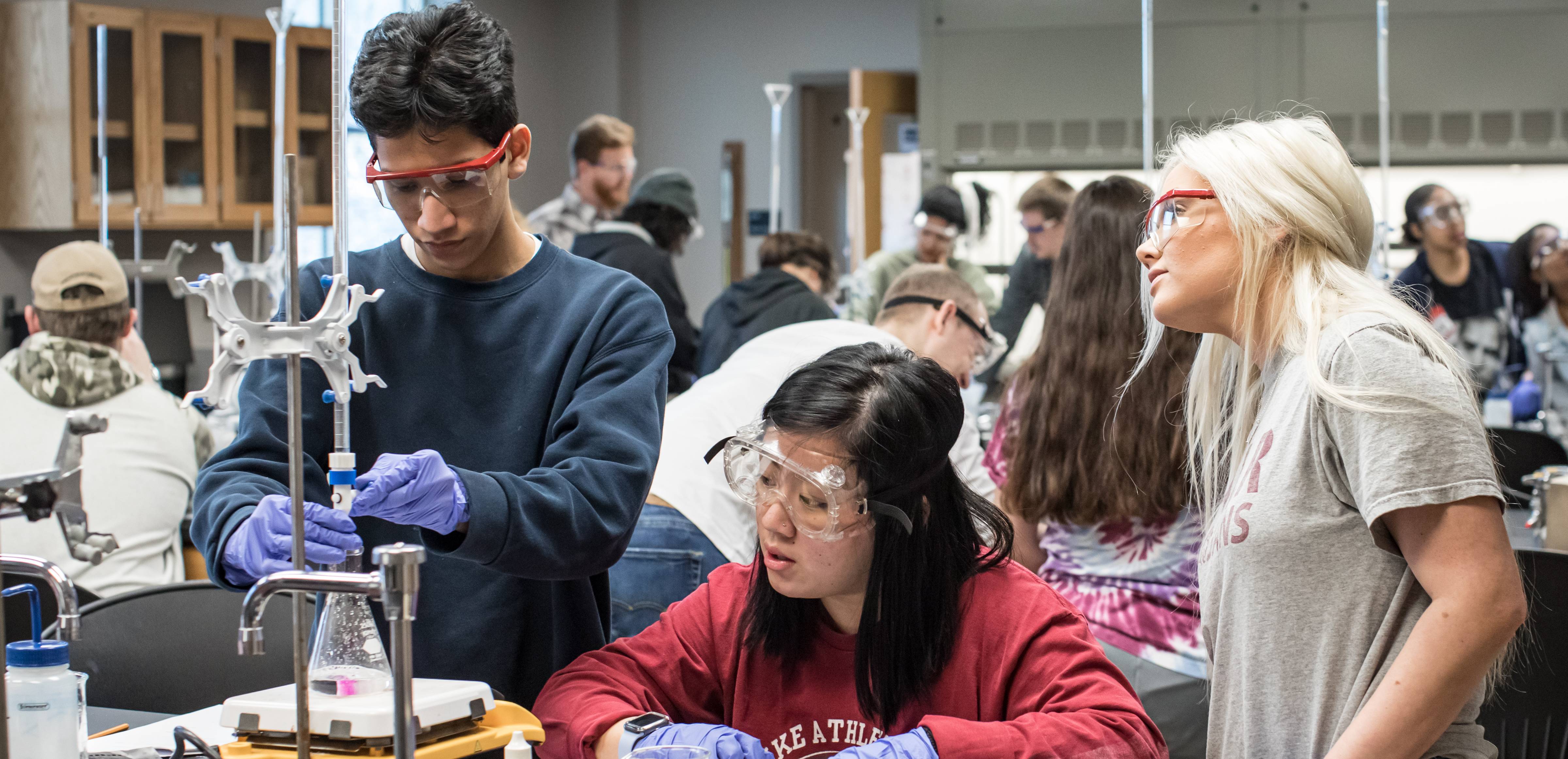 Group of chemistry students in a lab working with a beaker