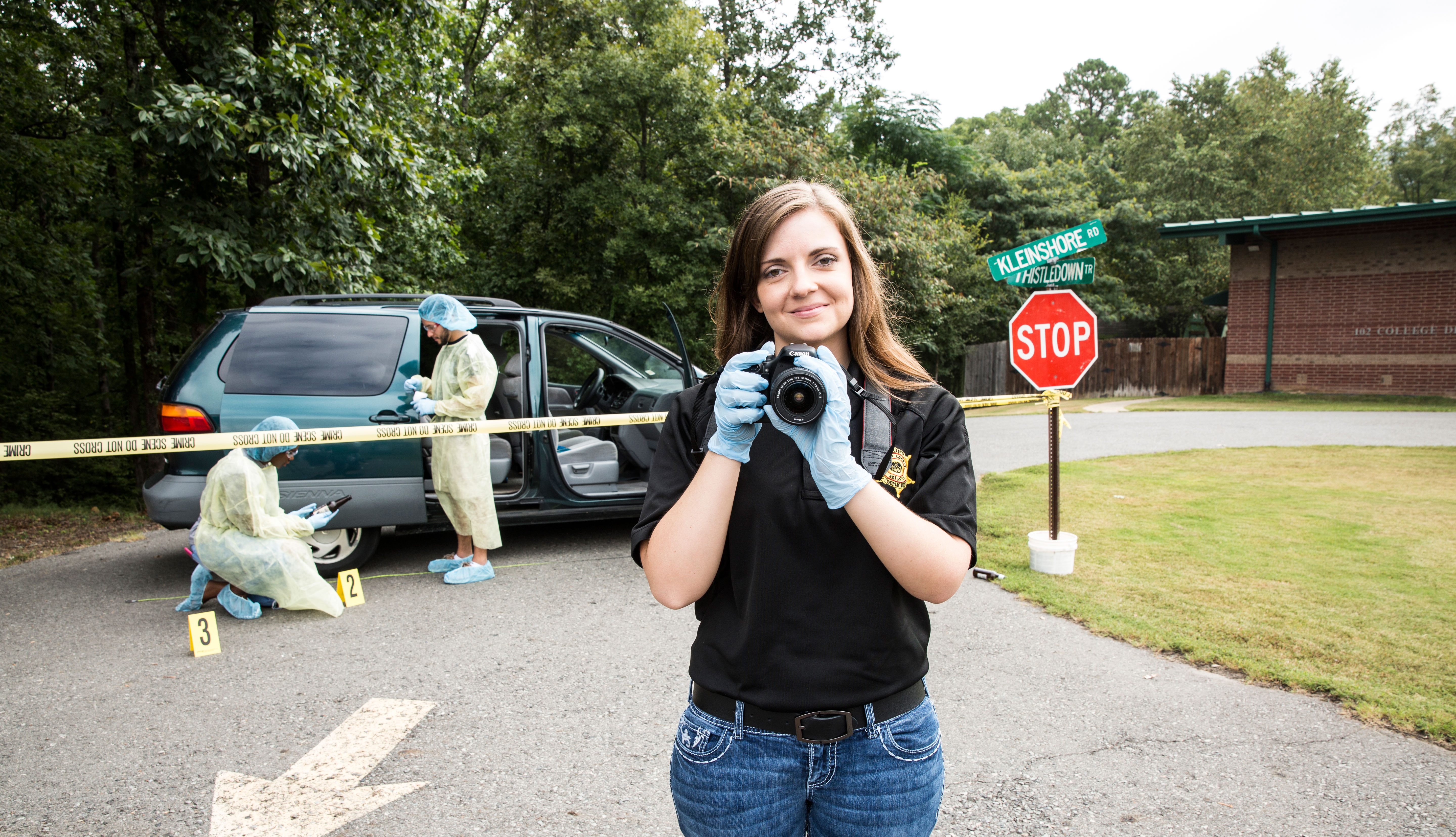 Two students working on crime scene and one student holding crime scene camera