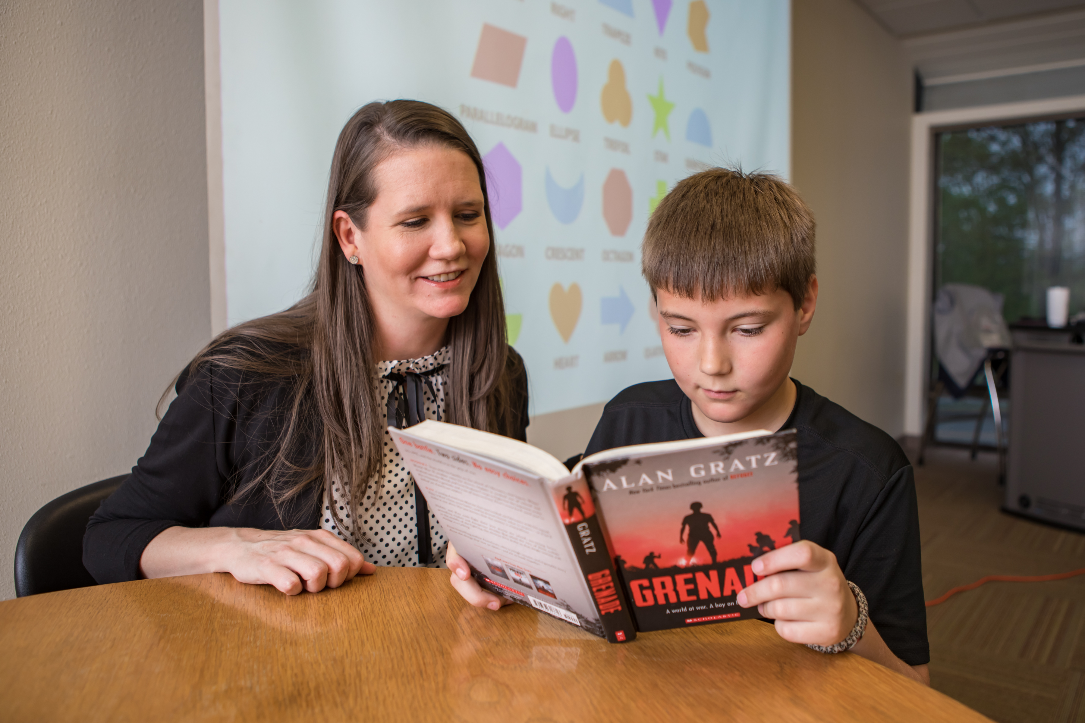 Teacher and student reading a book together