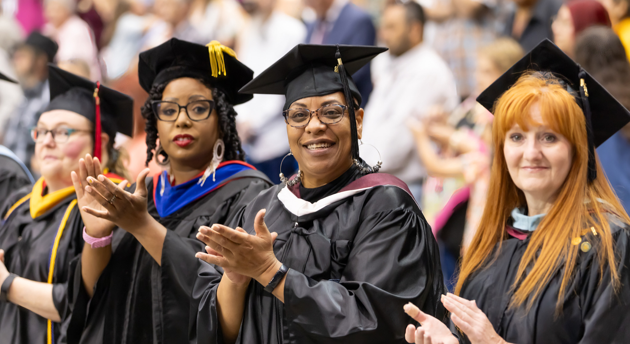 People in caps and gowns clapping.