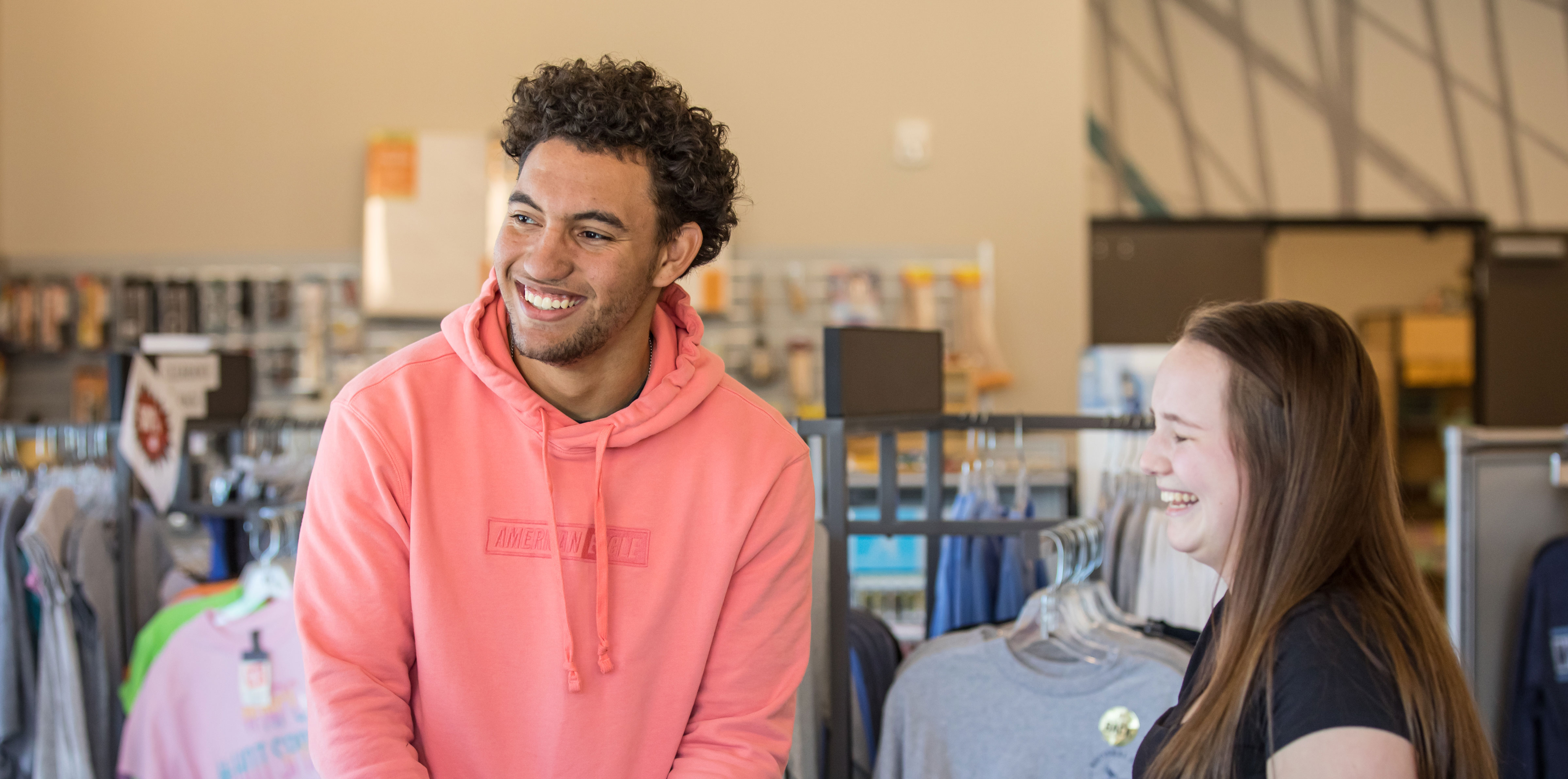 Male and female students smiling in book store