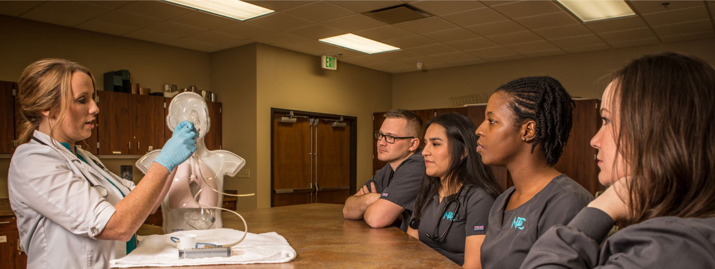 Nursing students watching a procedure on a dummy