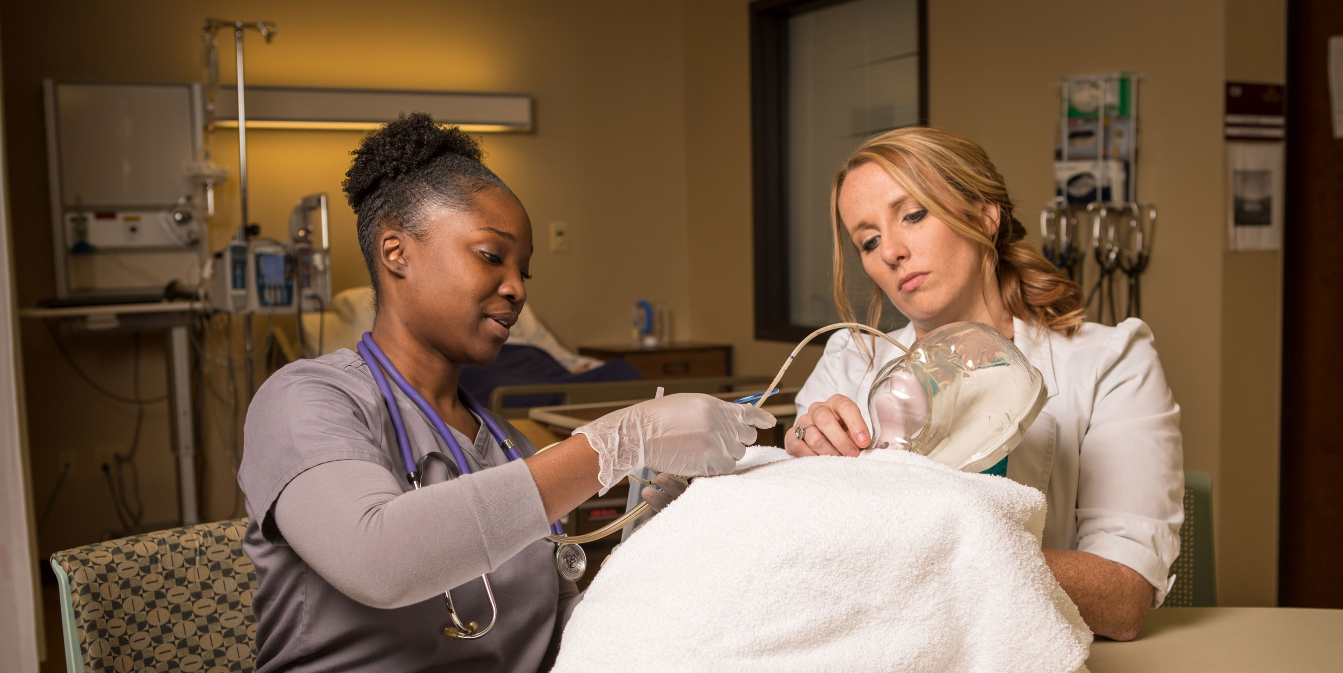 Nursing students practicing respiratory procedure on a dummy