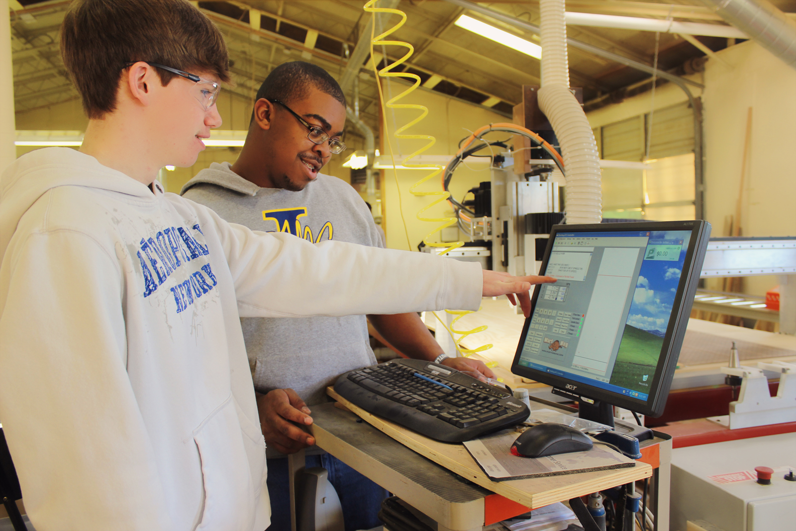 Two students working on computer in engineering workshop 