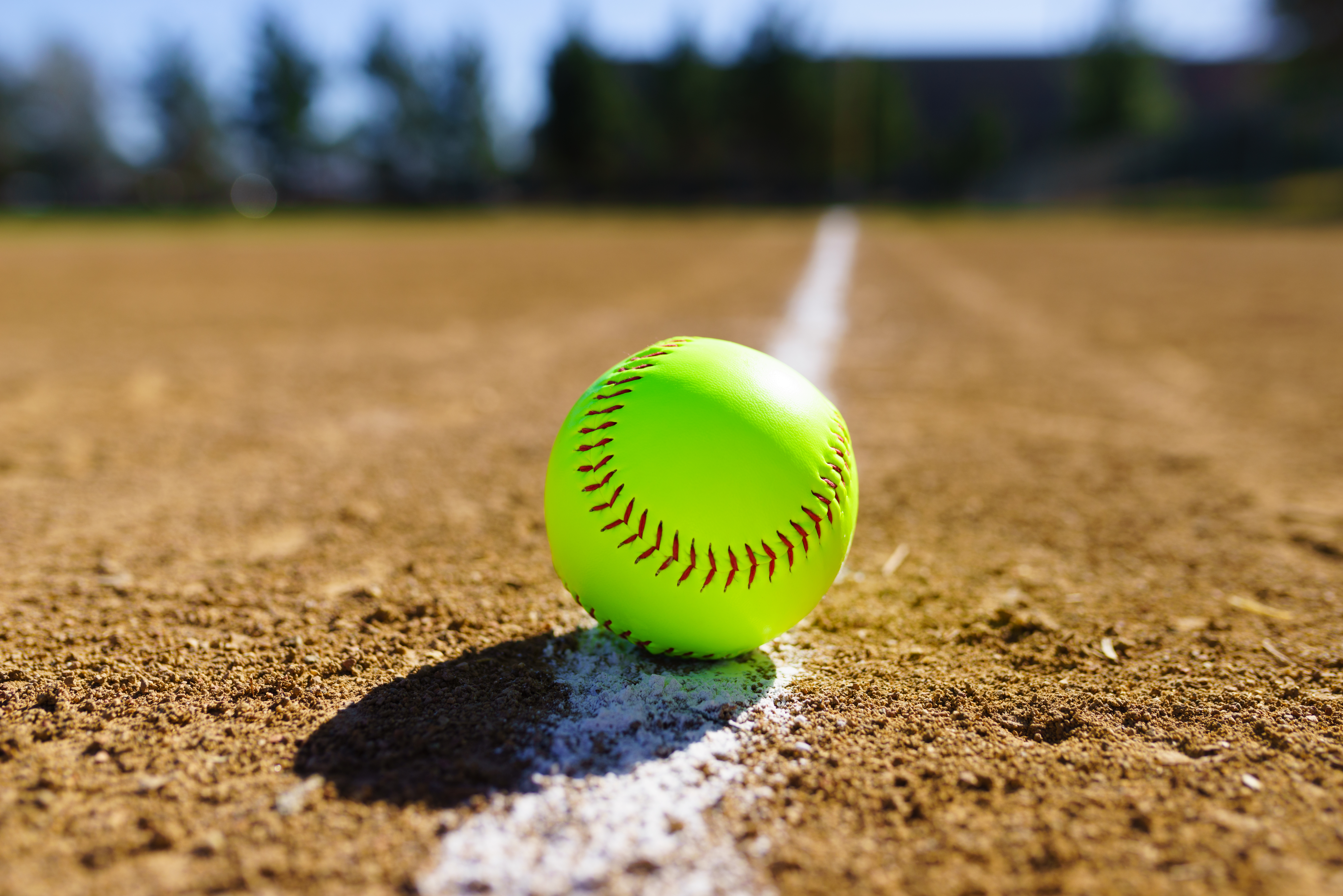 New yellow softball on dirt field