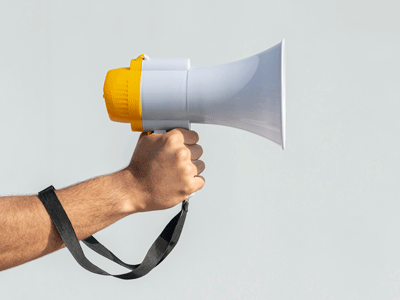 Hand holding a bullhorn on a gray background