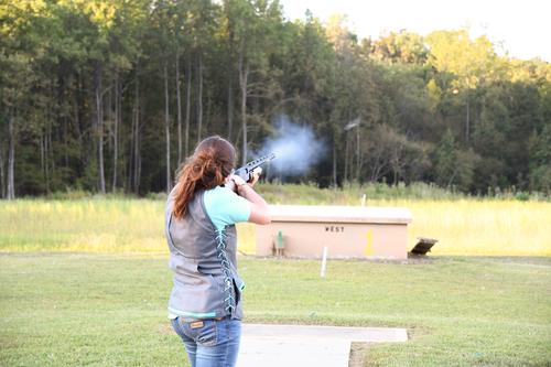 Person shooting a gun at a trapshooting target.