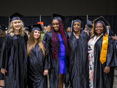 Five people in caps and gowns smiling at the camera.