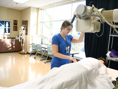 Student moving xray arm over patient.