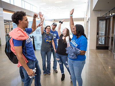 Students gathered around holding hands up to give high-fives.