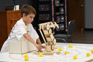 Young Manufacturers Camp, student using a robotic arm. 
