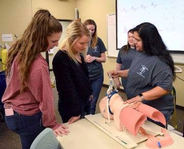 NPTC students Brianna Soliday (far left) and Cari Sibley (middle) from Jessieville High School look on as respiratory therapy students Renae Bradley, Sarah Love, and Hemal Patel demonstrate how to use a ventilator to breath for a patient.