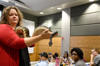 Barbara Parks holding snake while students, faculty, and staff observe