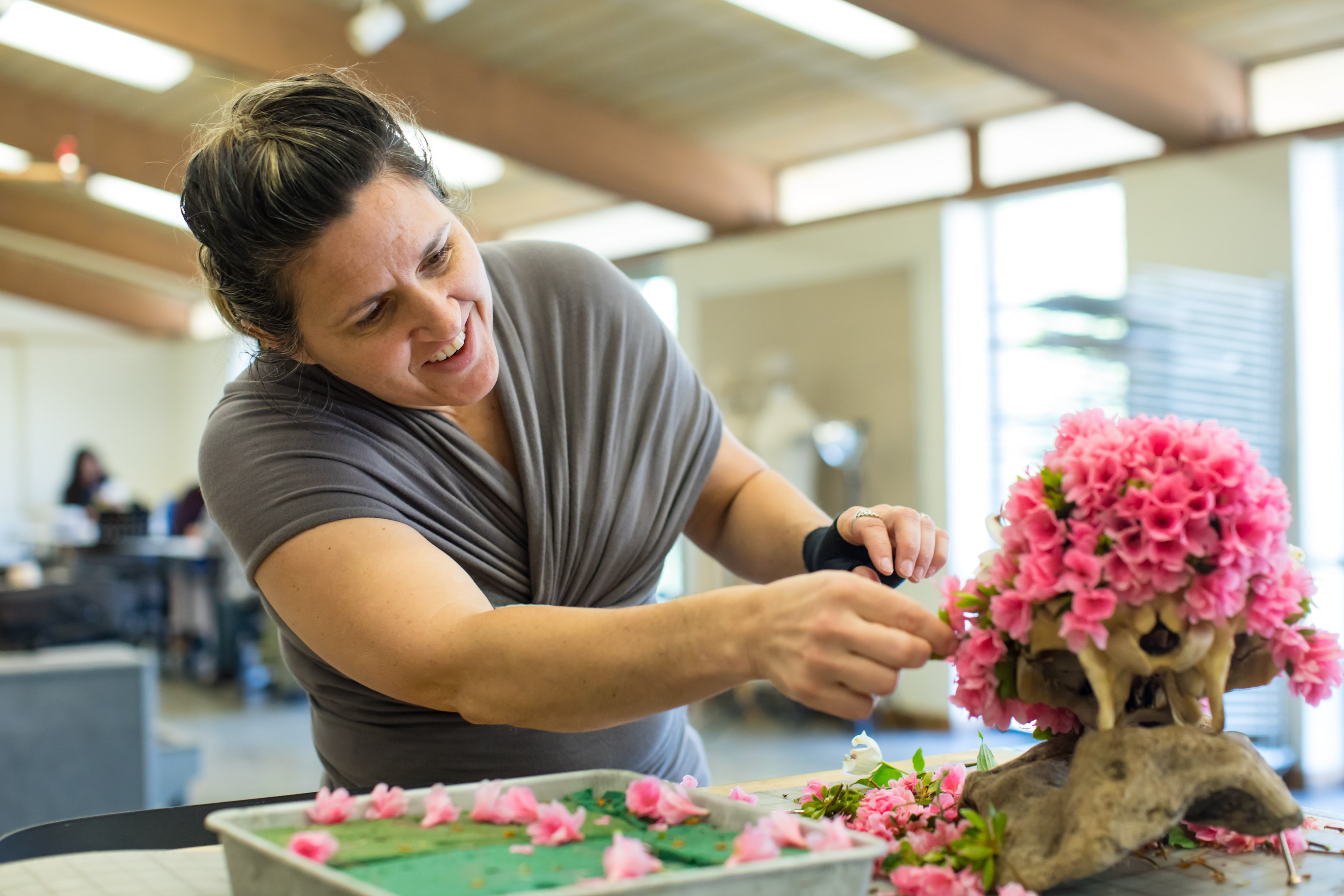 Angie Hoagin decorating a sculpture with pink flowers