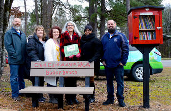 Team members of Child Care Aware standing behind their new reading bench and Little Free Library. 