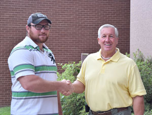 Jonathan Elmore shaking hands with scholarship provider Lloyd Robertson.