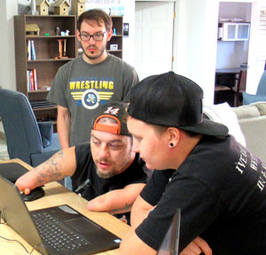 NPC student Jason Redfield, Ben Scarbrough and Leslie Slife consider the programming code for the prosthetic hand.