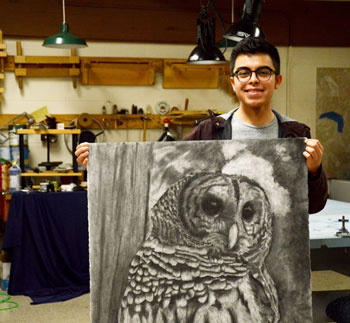 NPC student Ruiz Diaz with a charcoal drawing of an owl