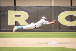 Jack Hackney diving over base to catch baseball.