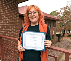 Student holding certificate for winning writing contest.