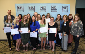 Twelve nursing students and 4 CHI staff standing in front of the NPC backdrop.