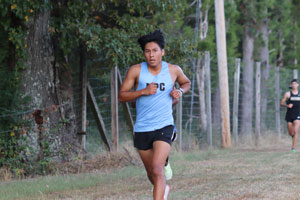Cross Country runner Miguel Mendez running on path in front of other runners.