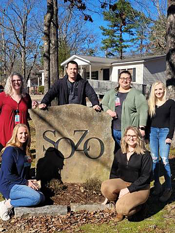 Nursing students surrounding SOZO sign.