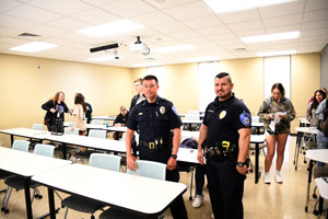 Two police officers standing in front of students in classroom.