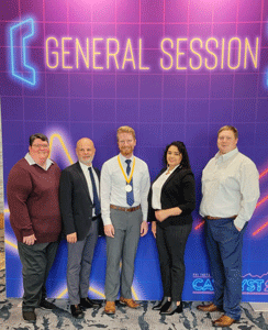 Two women and three men standing in front of a sign that looks neon that says General Session, Phi Theta Kappa Catlyst