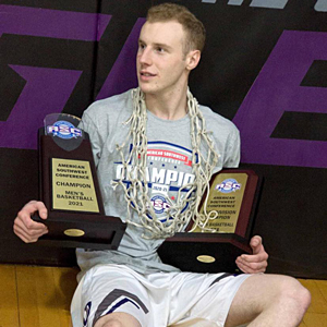 Basketball player Seth Duke holding two trophies with a basketball net around his neck.