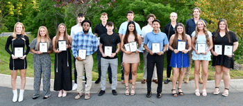 Group of people standing outside holding awards.