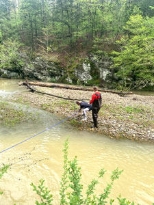 Two people pulling lines across a creek.