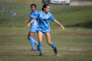 Two women soccer players on field anticipating the ball.
