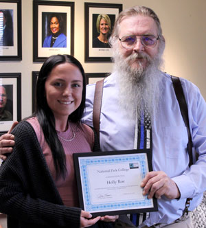 A student and a teacher standing together holding a certificate.