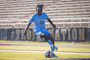 Soccer player Paulo Ndenzako kicking ball down field.