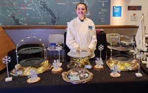 Hospitality student behind table with trays for hors d'oeuvres.