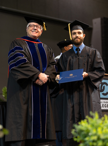 Jordan Terry on the graduation stage with Dr. David Lanoue, Provost and Vice President for Academic Affairs at SAU