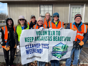 People holding sign that says Volunteer To Keep Arkansas Beautiful Cleanup This Weekend