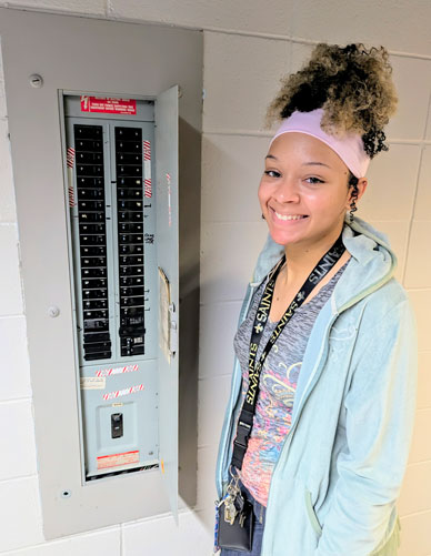 Laila Elliott standing next to a fuse box.