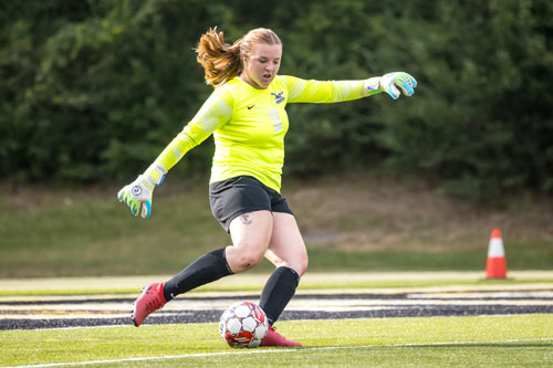 NPC women's soccer goalie rears back to kick the ball away from the net.