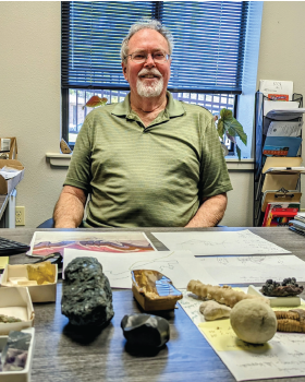 Stitting behind a desk is Dr. George Maxey.