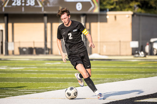 Soccer player Patrick Irving controling the ball down the field.