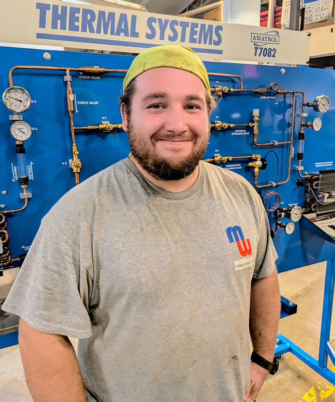 Steven Steuart standing in front of a Thermal Systems sign with pipes and guages.