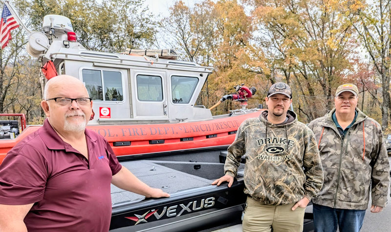 Three people standing in front of a Vexus brand boat.