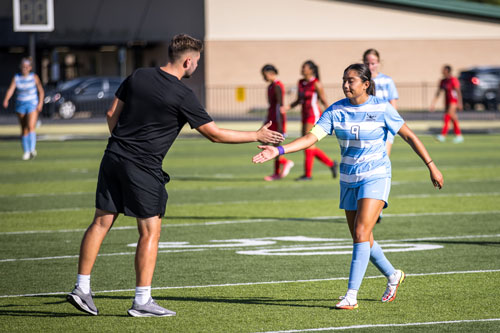 Coach and player for NPC giving each other a hand slap.