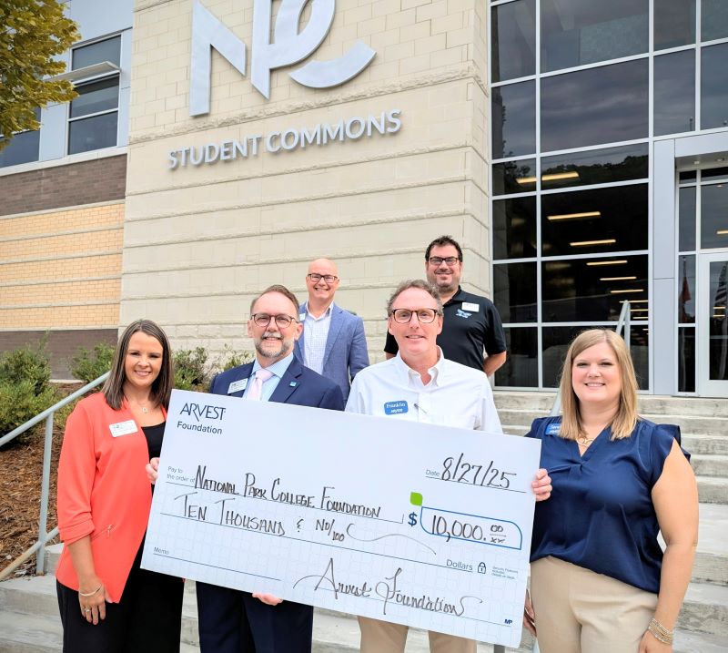 Several people standing on stairs in front of NPC Student Commons holding an oversize check.