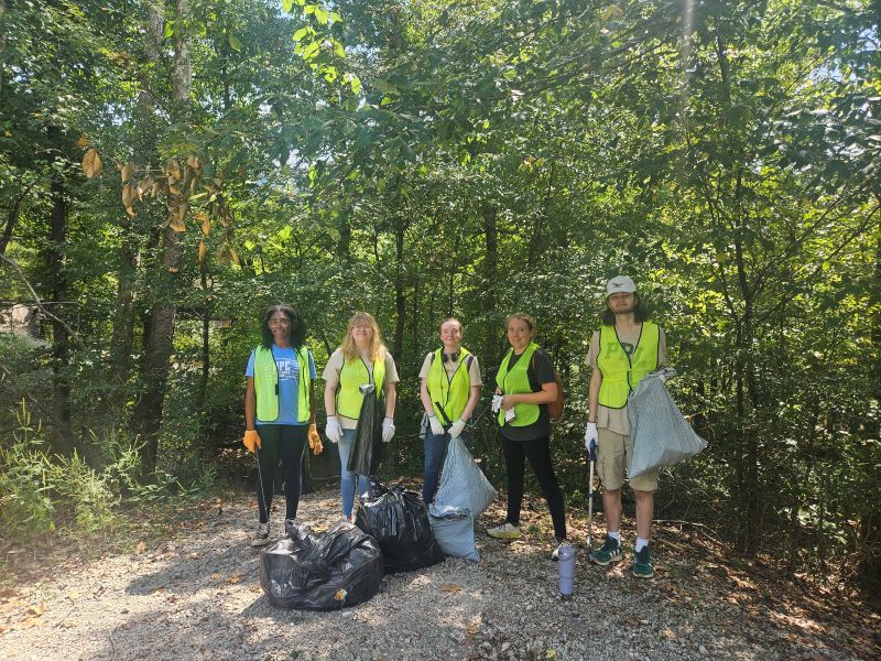 Five people with trash bags and reflective vests.